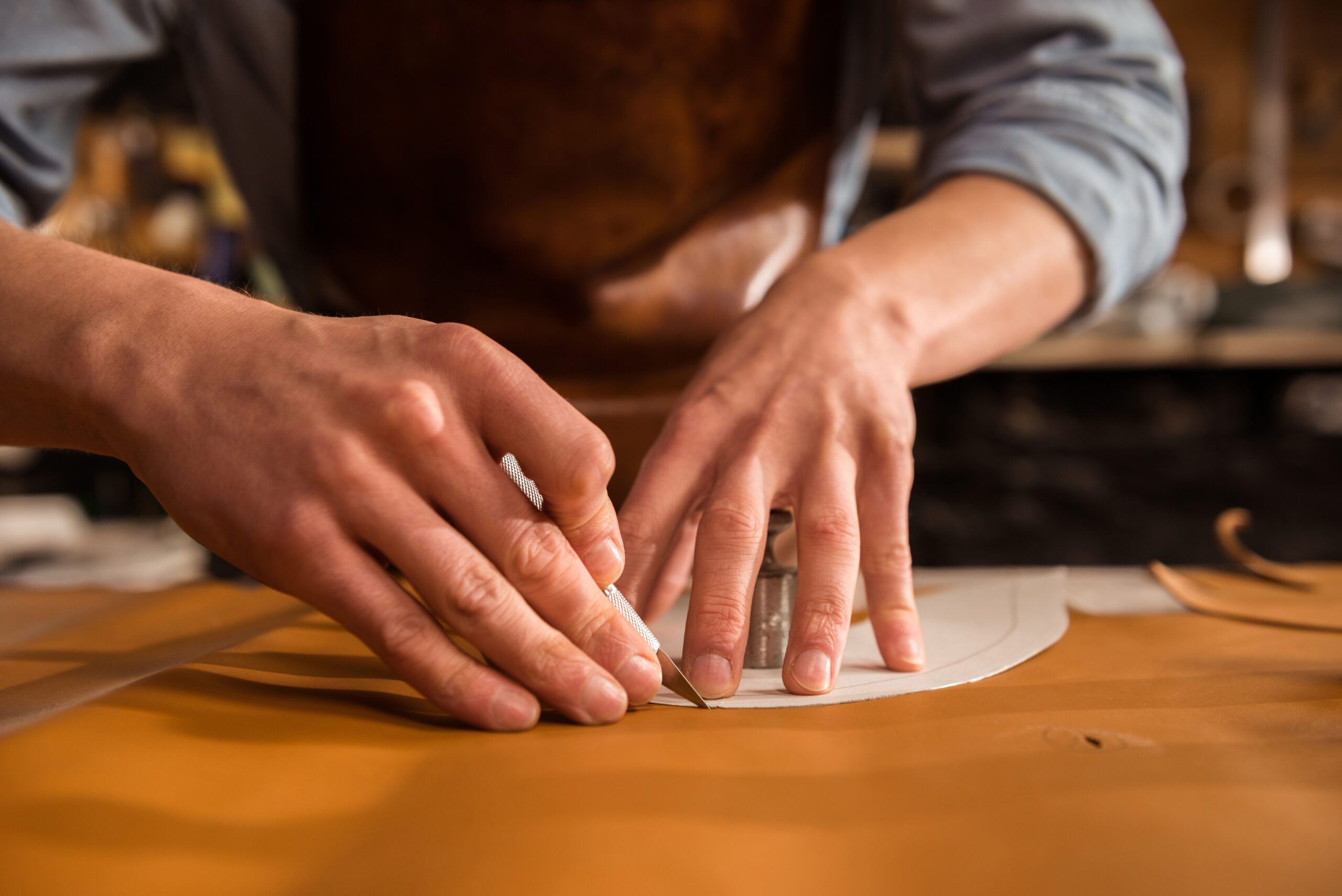 Close up of a shoemaker cutting leather in a workshop